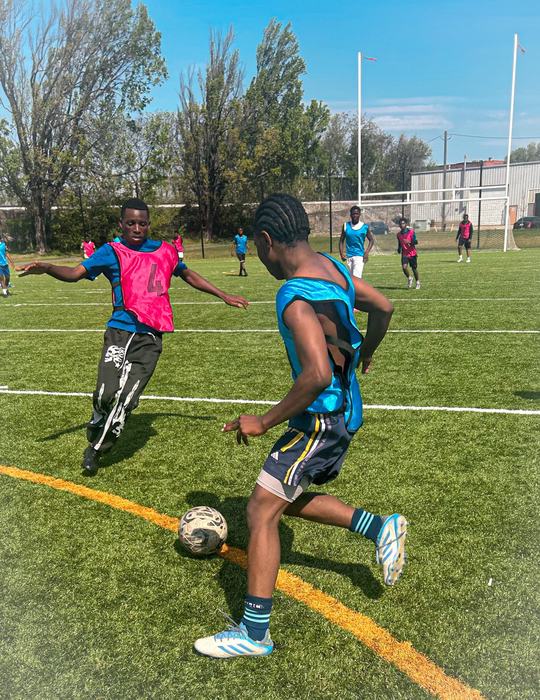 Warriors Soccer Camp player dribbling past a defender